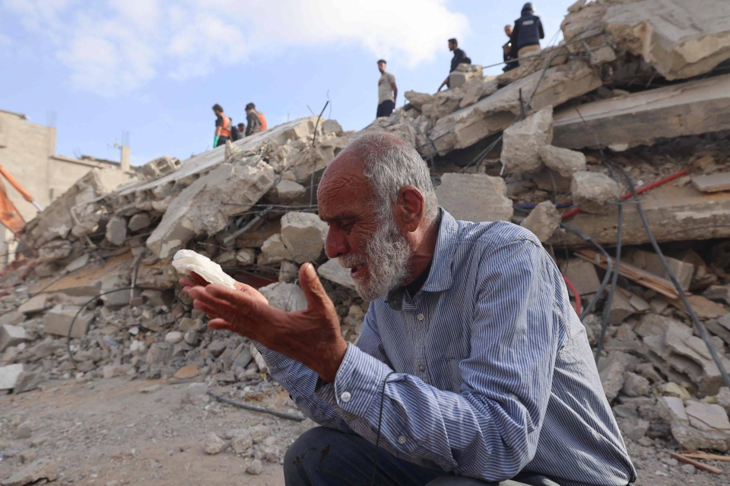 رجل فلسطيني ينتظر أخباراً عن ابنته إذ يبحث عمال الإنقاذ عن ناجين تحت الأنقاض في رفح إثر غارة إسرائيلية (أ.ف.ب)