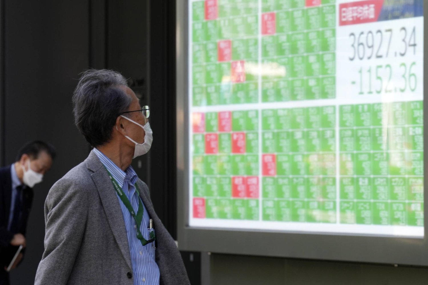 رجل يتابع حركة الأسهم على شاشة كبيرة في مركز للتداول وسط العاصمة اليابانية طوكيو (أ.ب)